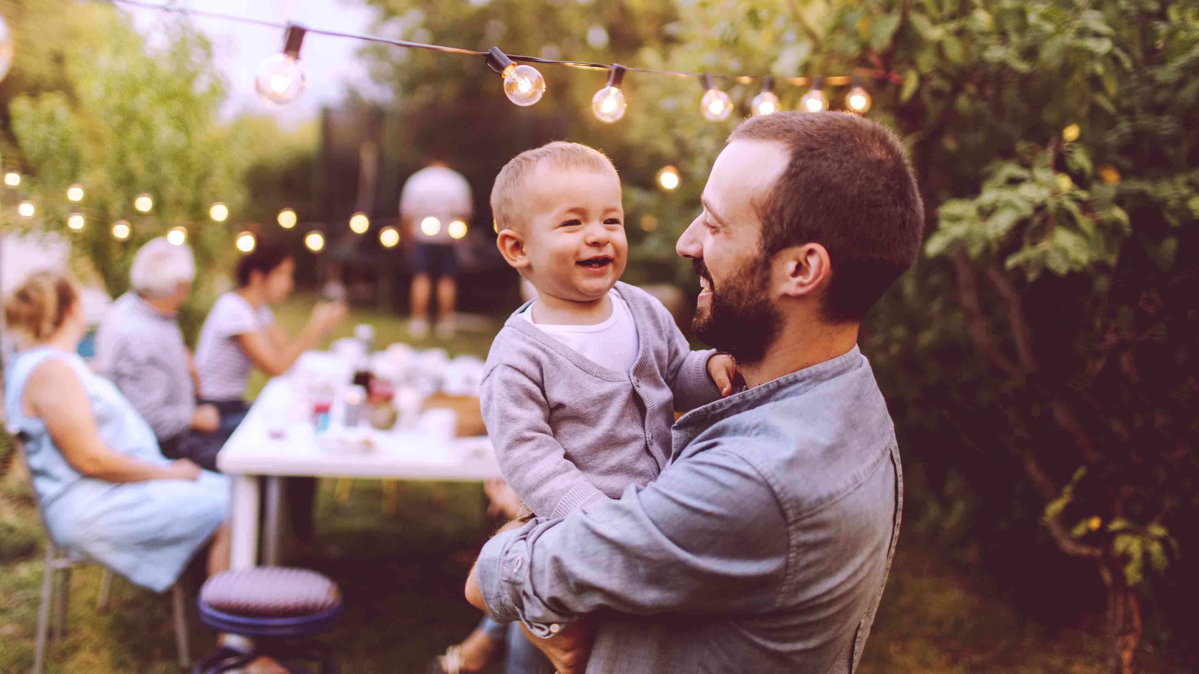 Man holding smiling baby in a garden